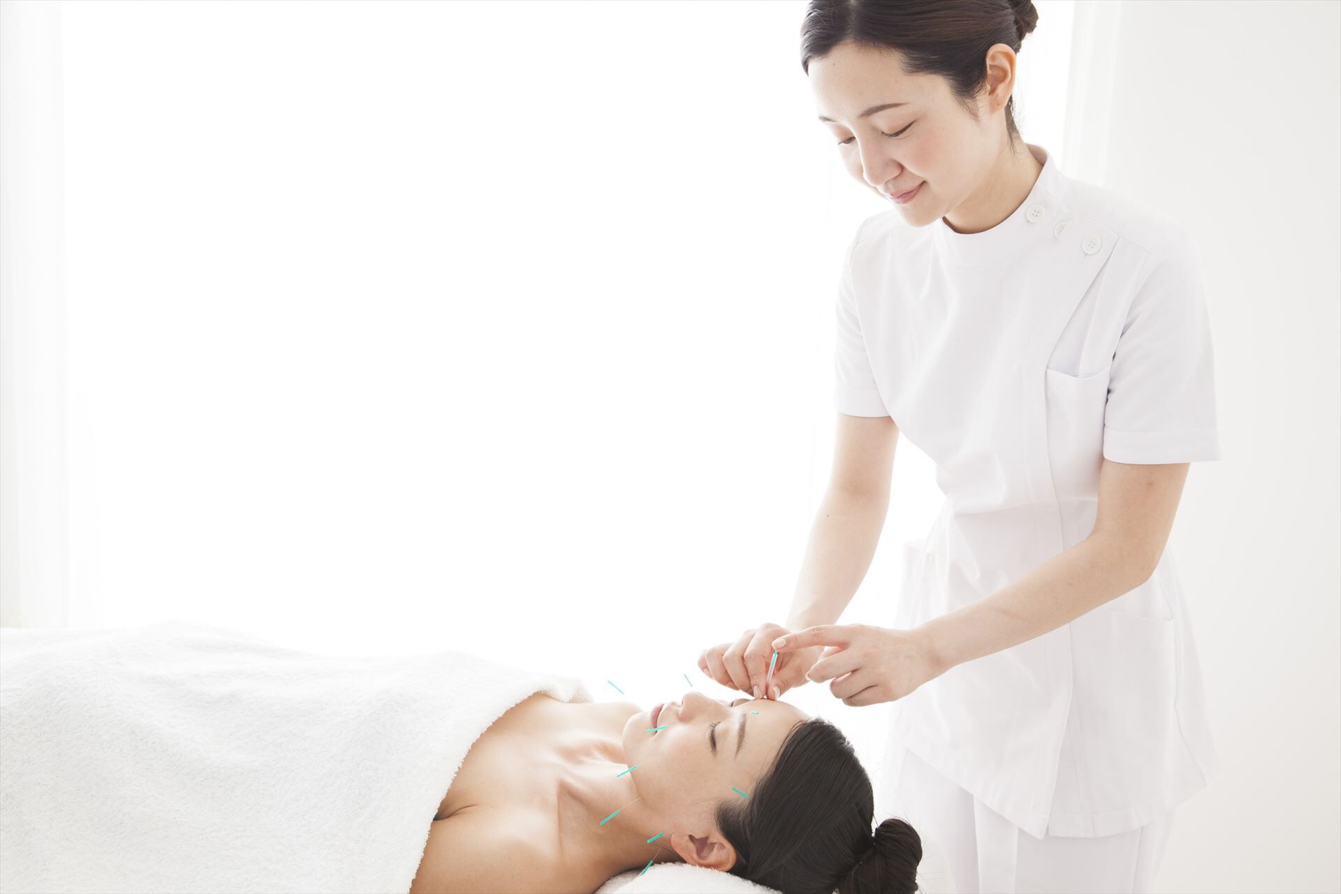 顔に鍼を打つ女性スタッフ